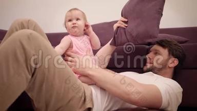 <strong>爸爸</strong>在沙发上和婴儿玩。 神父时间。 快乐的<strong>爸爸</strong>和女儿